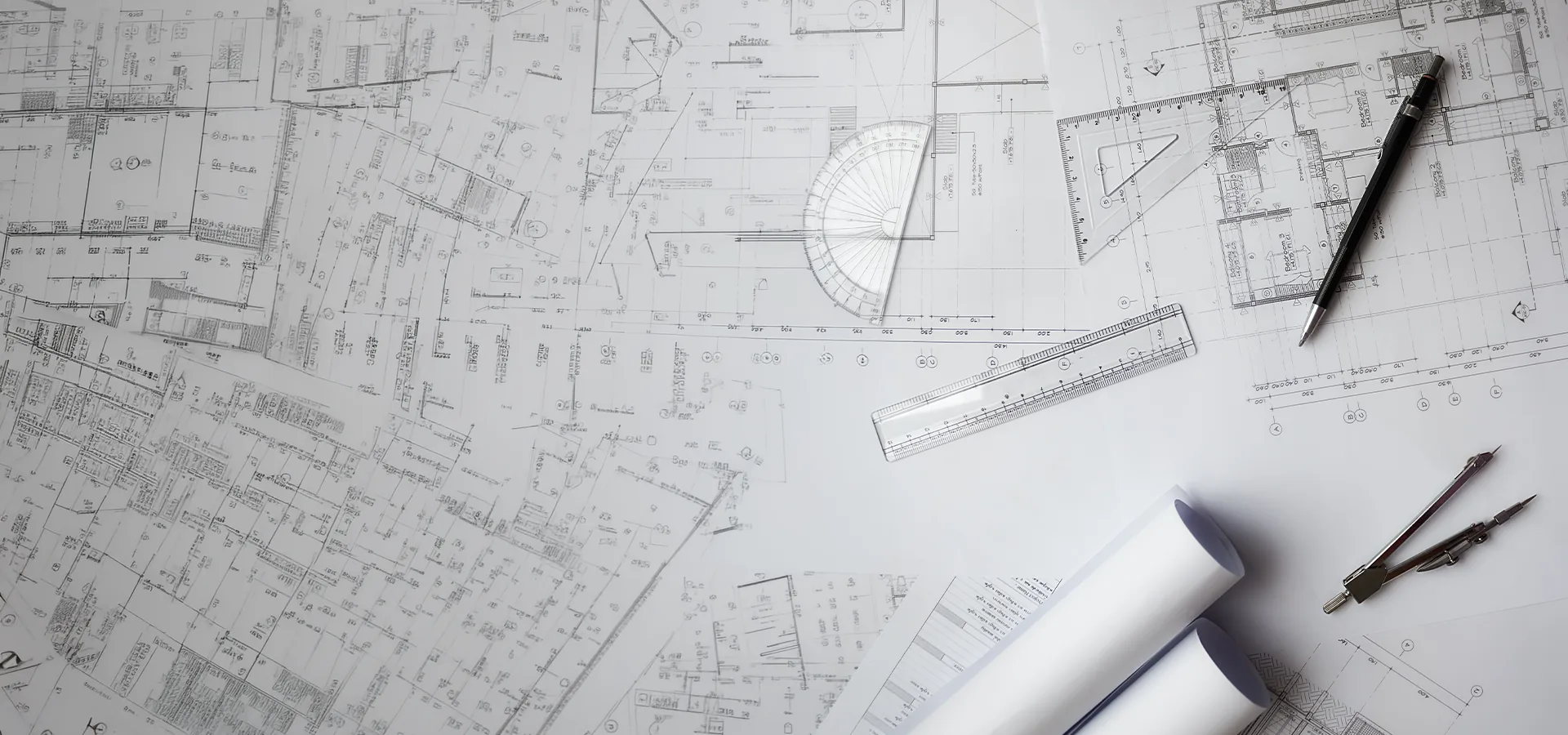 Architectural floor plans, set square and drafting tools laid out on a desk