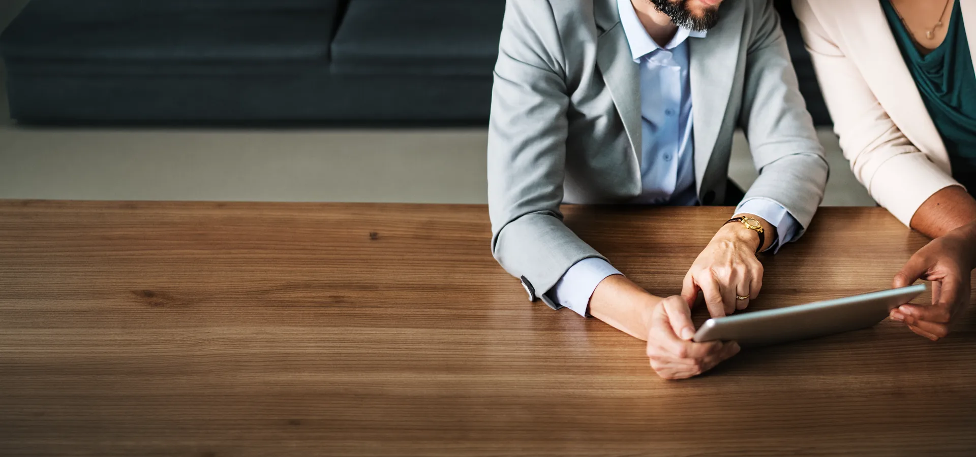 Consultant and client seated at a timber table reviewing slip testing details on a tablet